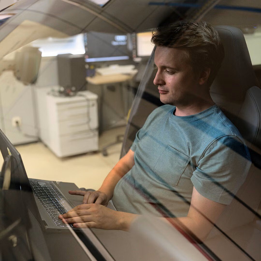 Jan Totz sedi na sovoznikovem sedežu Audija in gleda v prenosni računalnik.