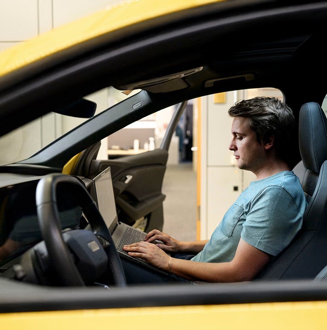 Jan Totz sedi na sovoznikovem sedežu Audija in gleda v prenosni računalnik.