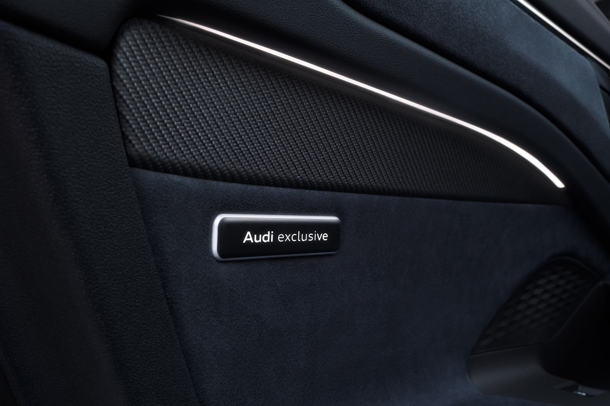 Logotip Audi exclusive v vratni oblogi pod dekorativnim elementom.