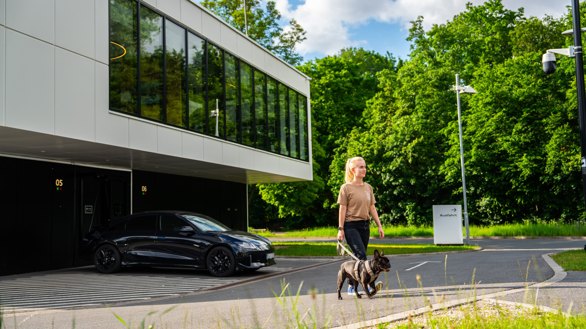 Ženska s psom na povodcu odhaja iz polnilnega središča Audi.