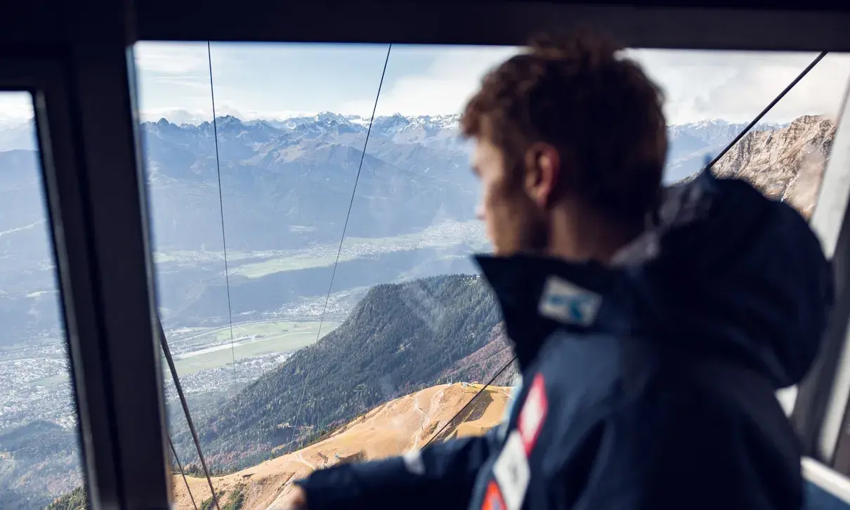 Kilde sedi v gondoli in gleda na Innsbruck pod njim.