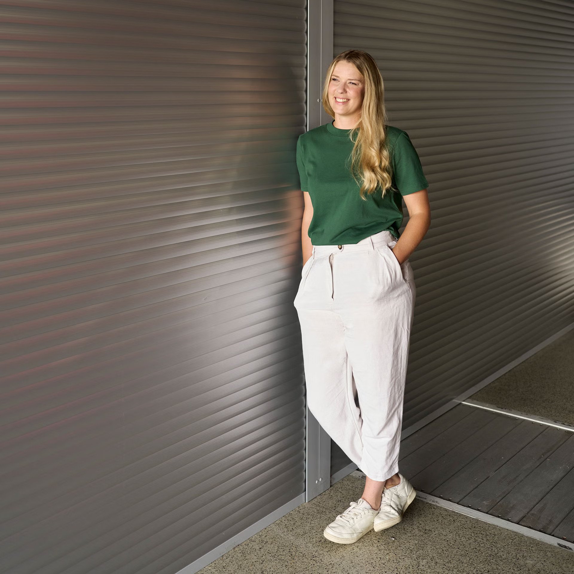 Lissi Lanz ima roke v žepih hlač in se naslanja na steno.