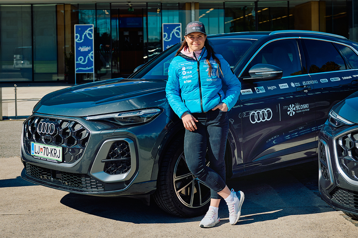 Neja Dvornik stoji pred avtomobilom Audi Q5.