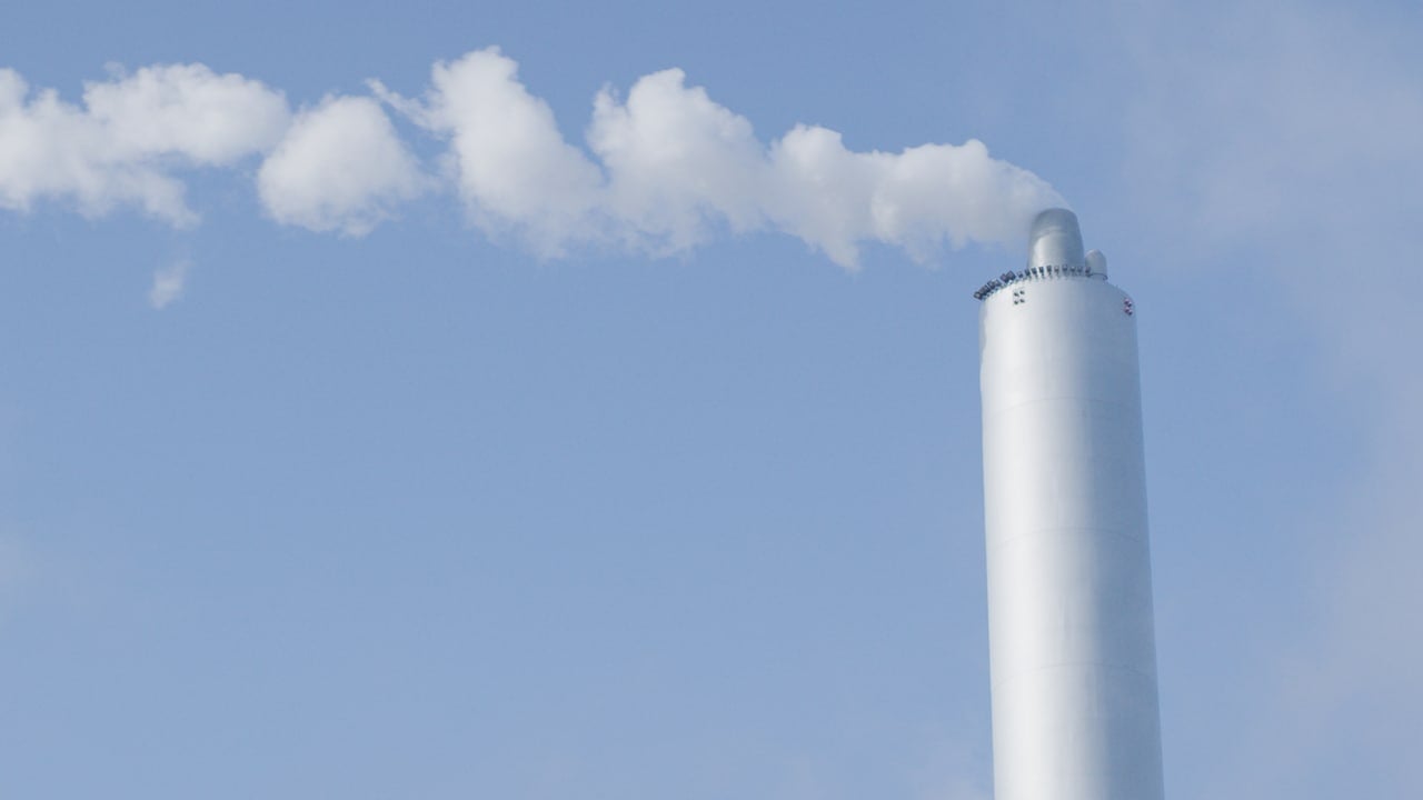 Dimnik, iz katerega se kadi bel plin, v ozadju modro nebo