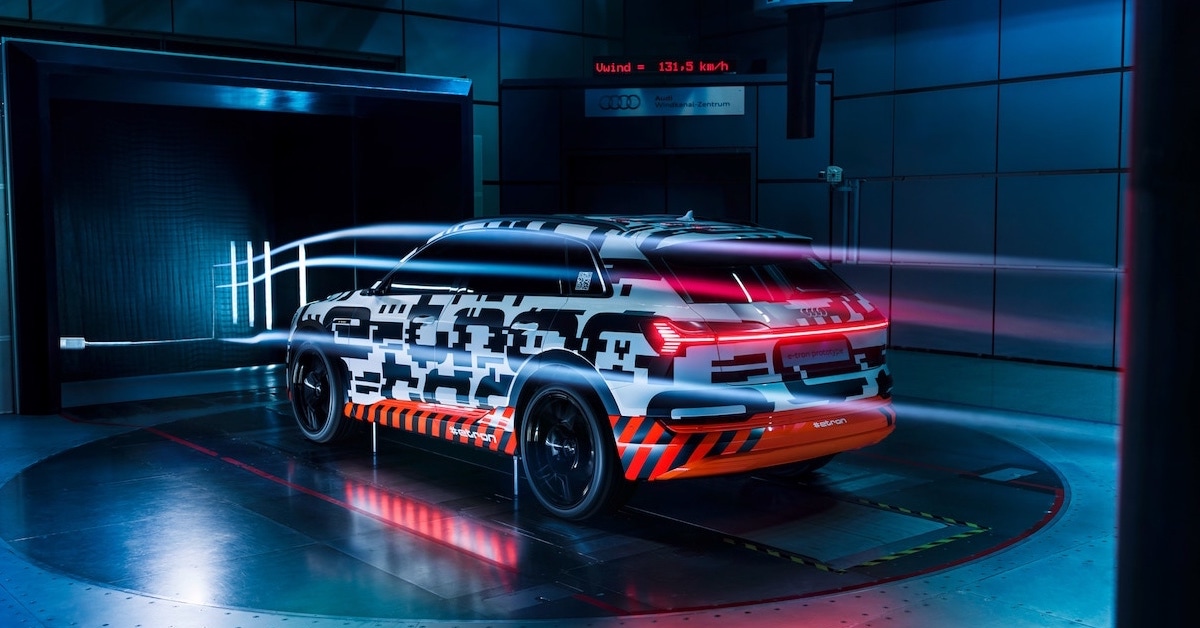 Prototip vozila Audi e-tron med testiranjem v vetrovnem tunelu. Slika je temna in avto ima prižgane zadnje rdeče luči