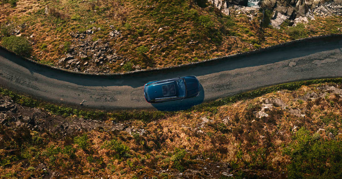 Modro vozilo Audi na podeželjski cesti. Ob cesti trava in nizko rastje