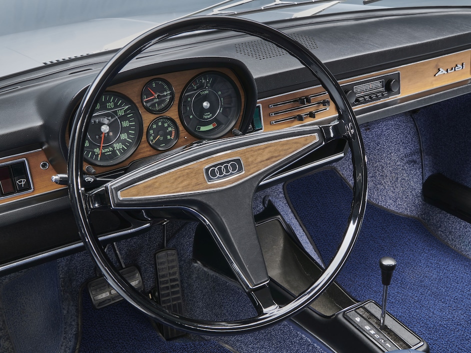Notranjost starega modela Audi z leseno armaturno ploščo.