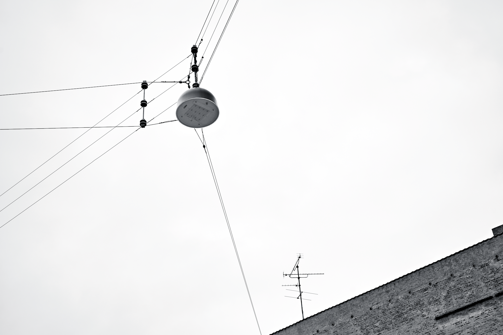 Črno-bela fotografija ulične svetilke v zraku na žici.