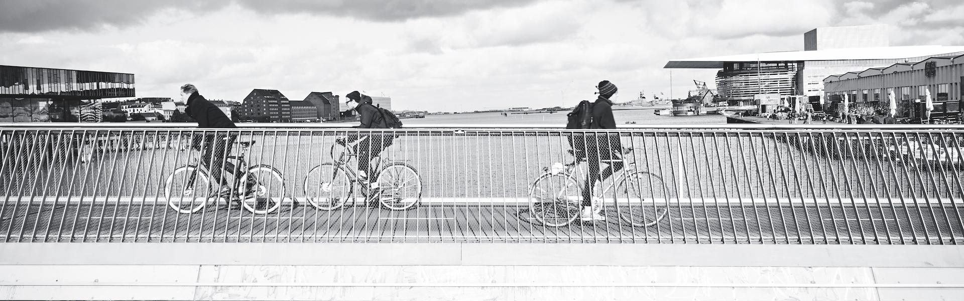 Most na katerem so trije kolesarji. Črno-bela slika.