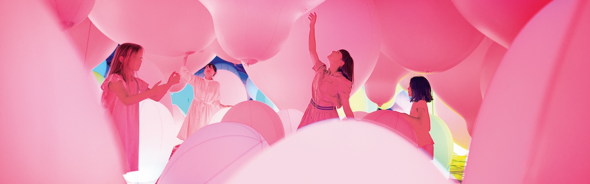 Štiri ženske med igranjem z roza velikimi baloni.