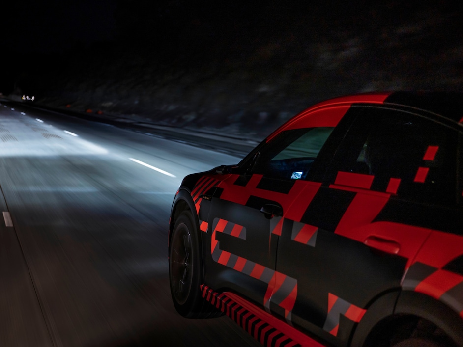 Audi e-tron na cesti ponoči. Slikano od strani.