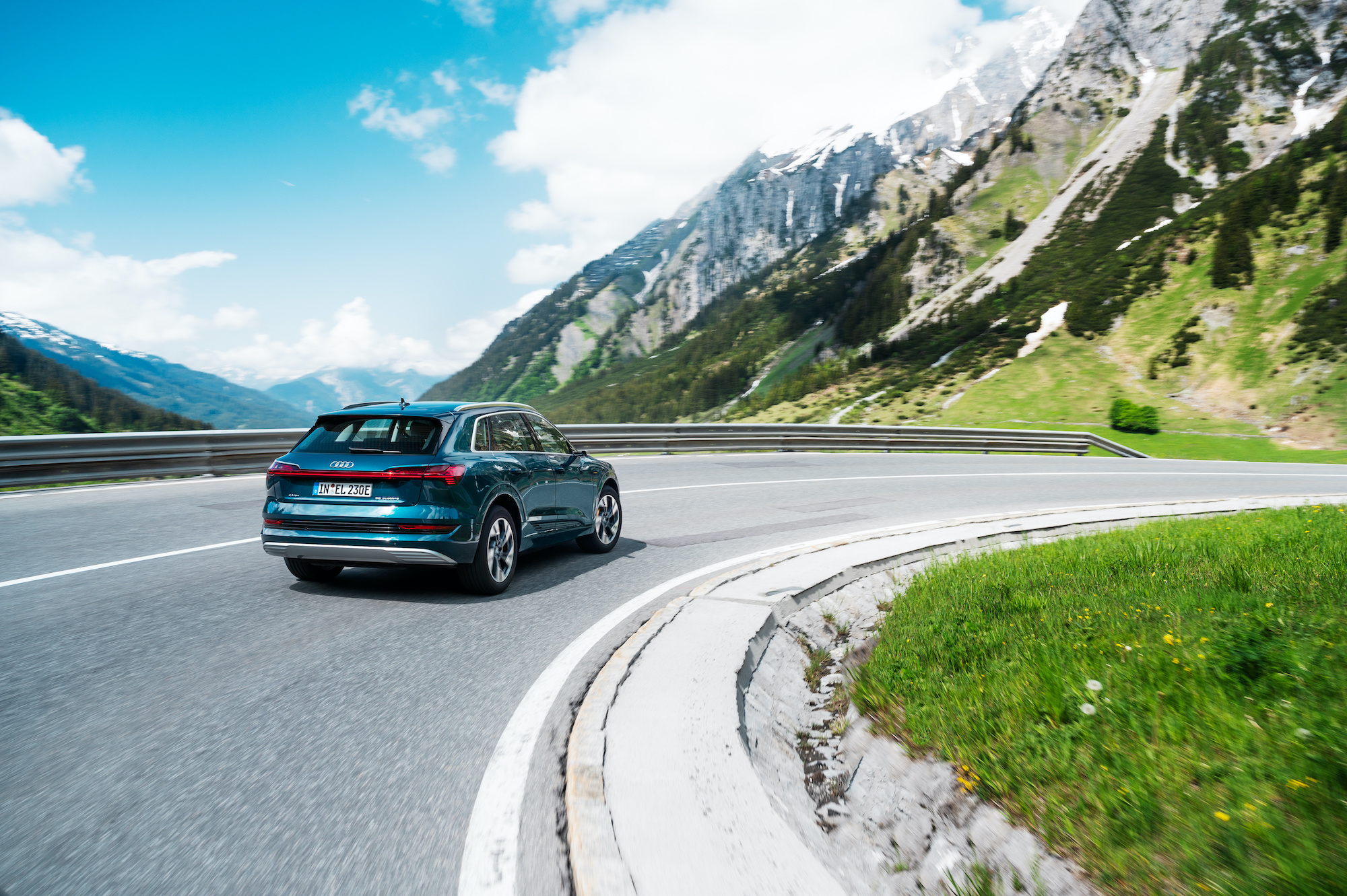 Audi e-tron na gorski cesti. V ozadju modro nebo in oblaki