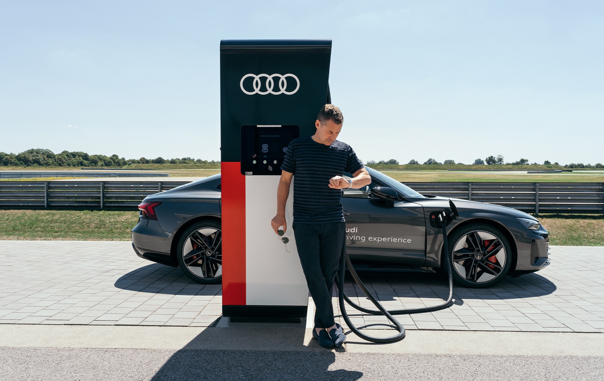 Tom Kristensen stoji ob polnilnici med polnjenjem vozila Audi RS e-tron GT.