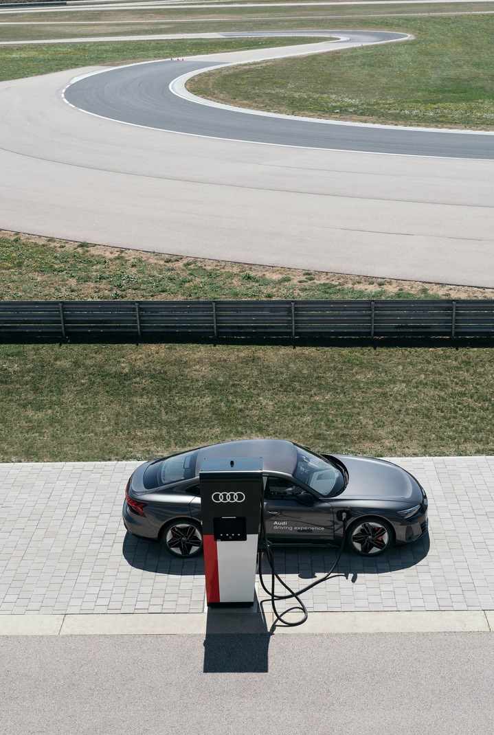 Audi RS e-tron GT med polnjenjem, v ozadju je dirkaška steza.
