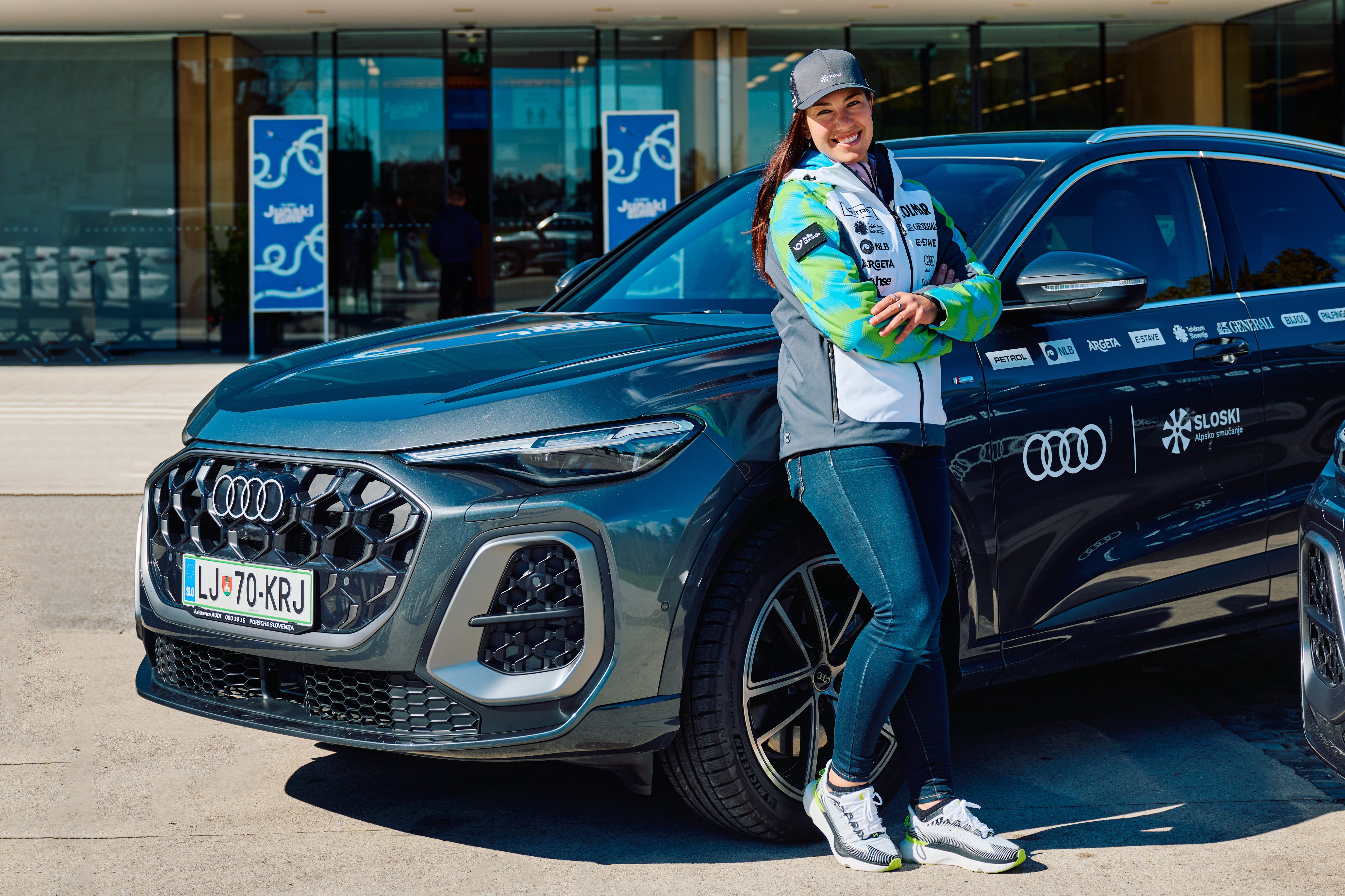 Lila Lapanja stoji pred avtomobilom Audi Q5.