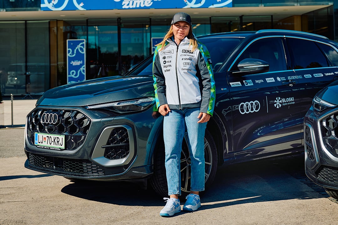Anja Oplotnik stoji pred avtomobilom Audi Q5.