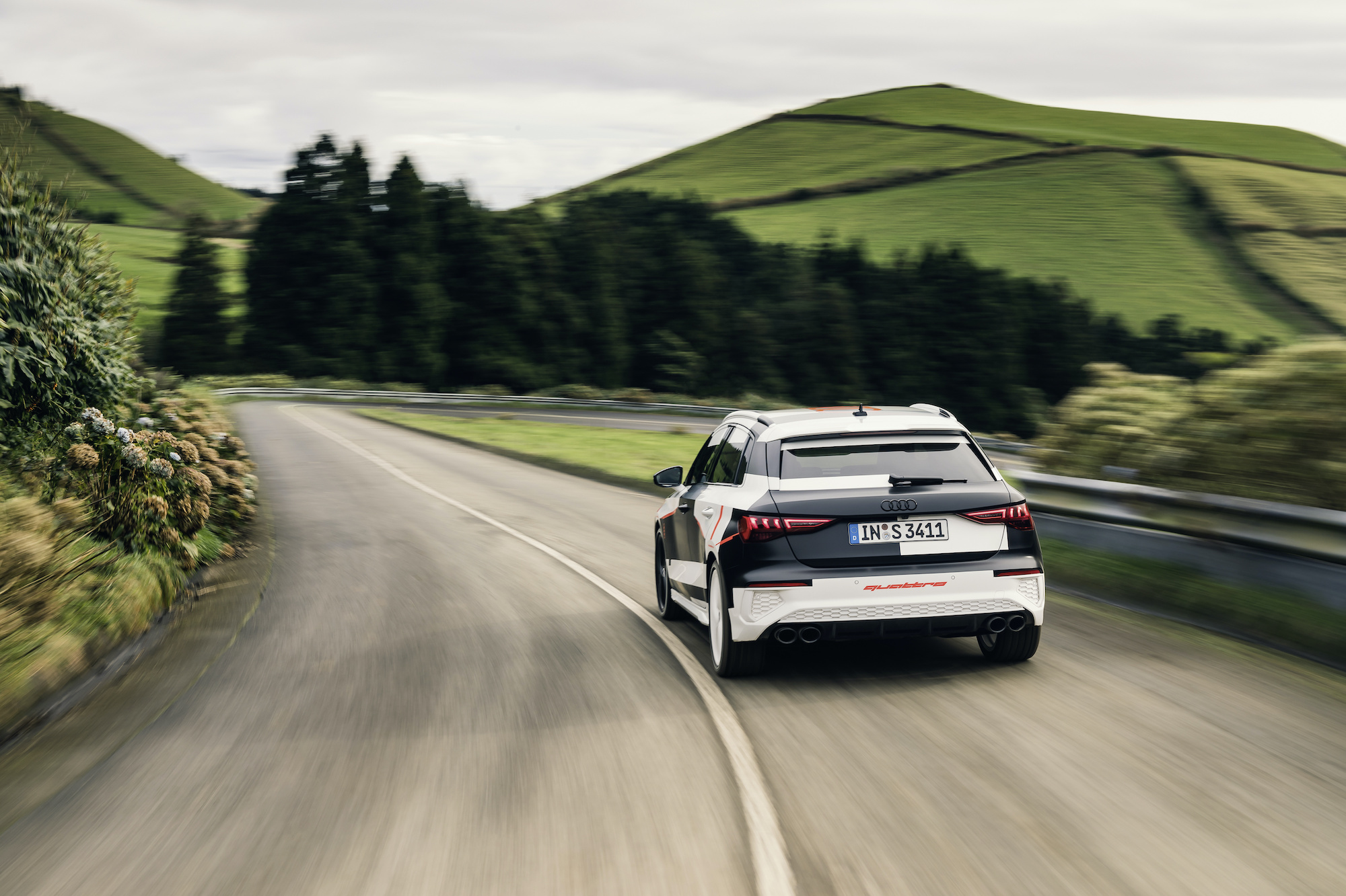 Audi quattro vozilo na podeželjski cesti. V ozadju drevesa in travniki