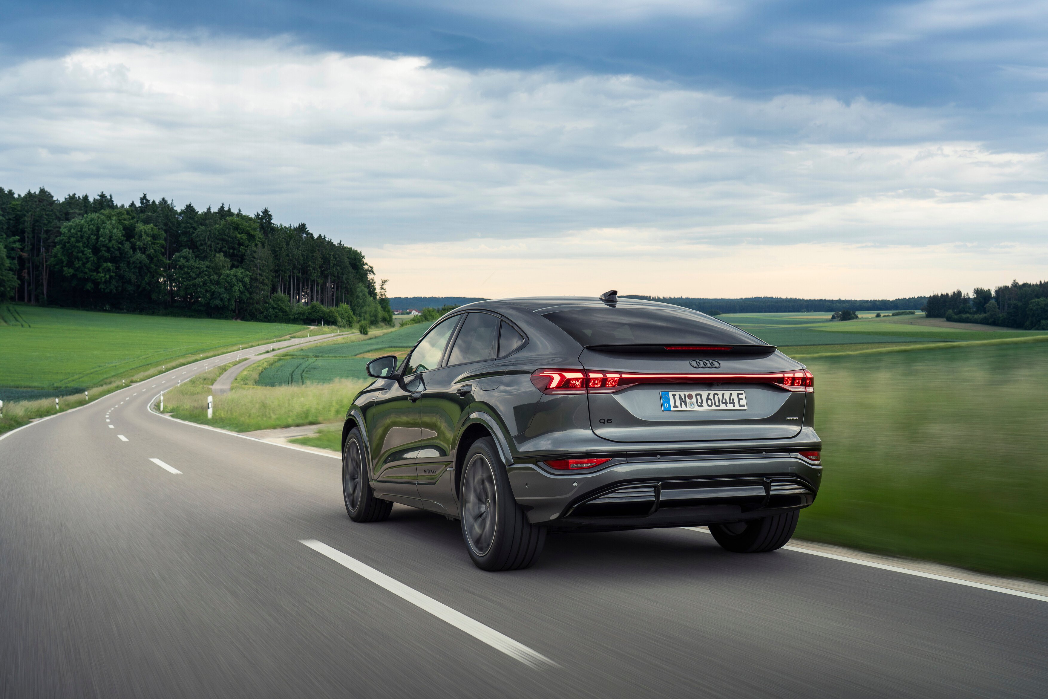 Audi Q6 Sportback e-tron od zadaj v vožnji po cesti.