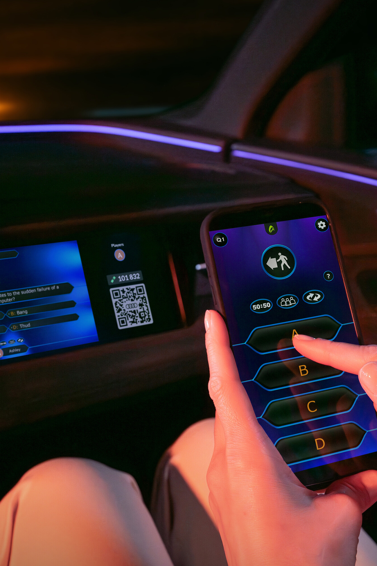 Oseba drži telefon pred zaslonom in ga uporablja kot krmilnik za igro ter izbiro odgovorov.