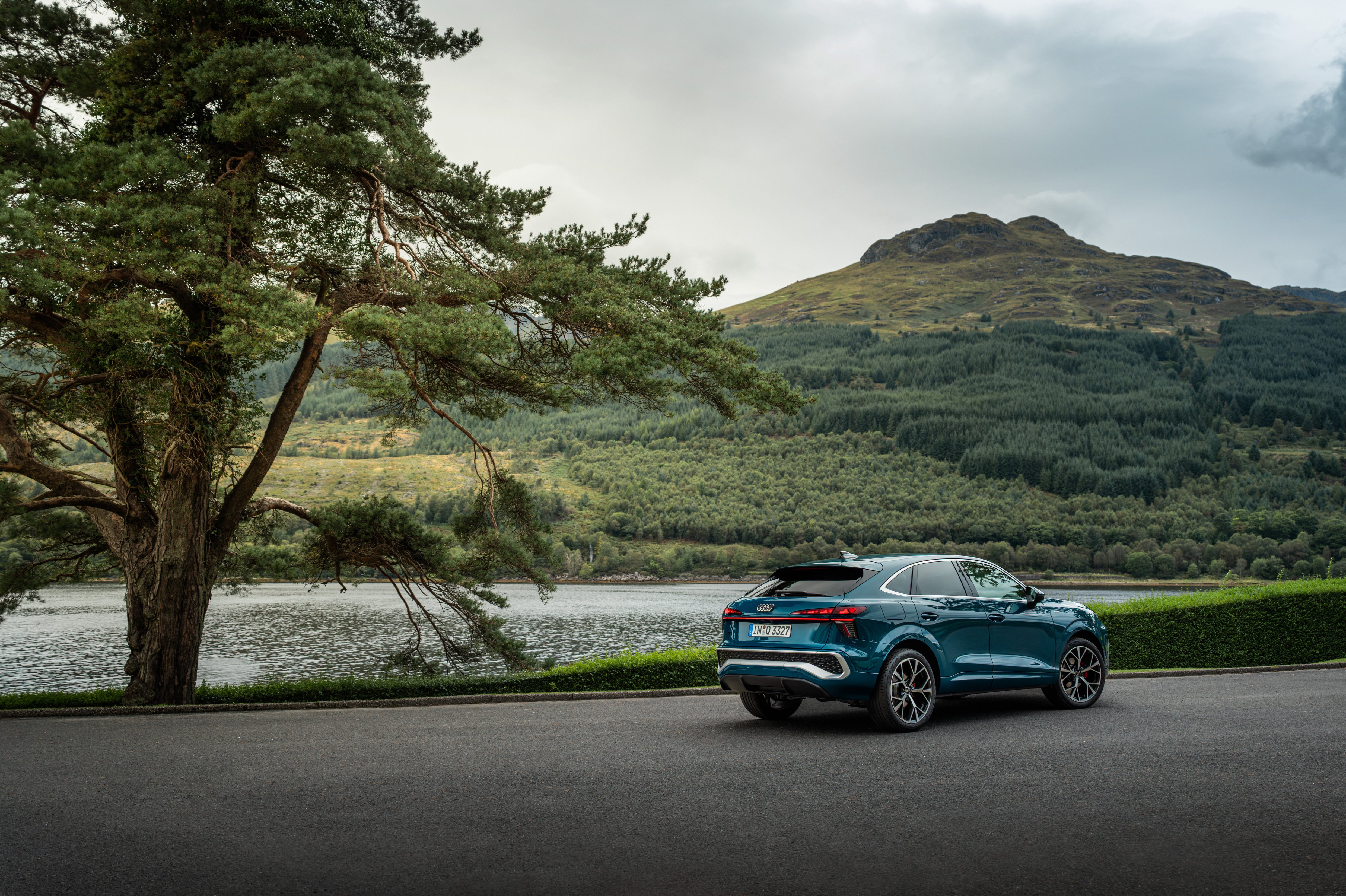 Modri Audi Q3 Sportback na cesti ob reki.