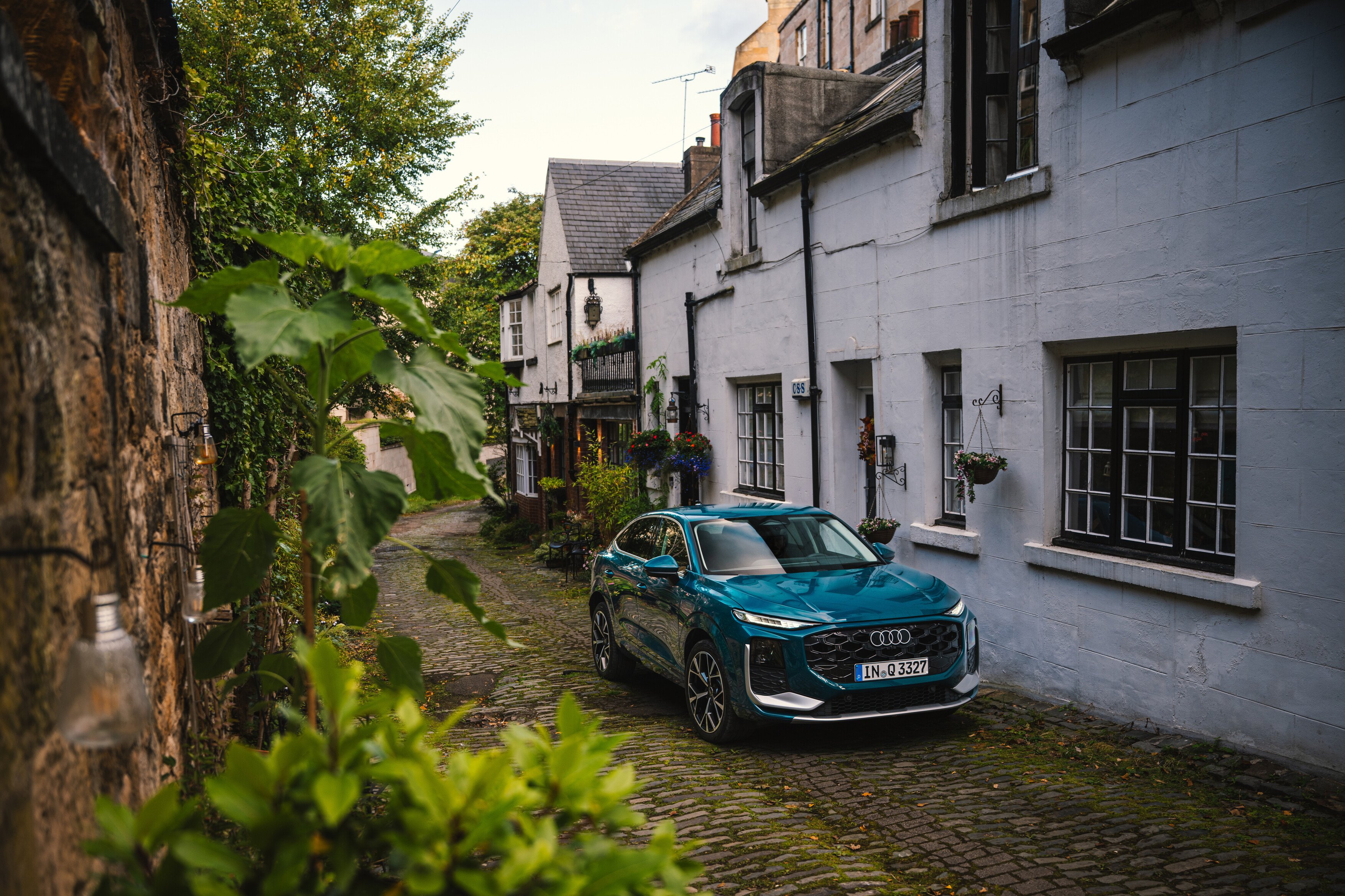 Modri Audi Q3 Sportback v slikoviti škotski vasici.er zelenjem.