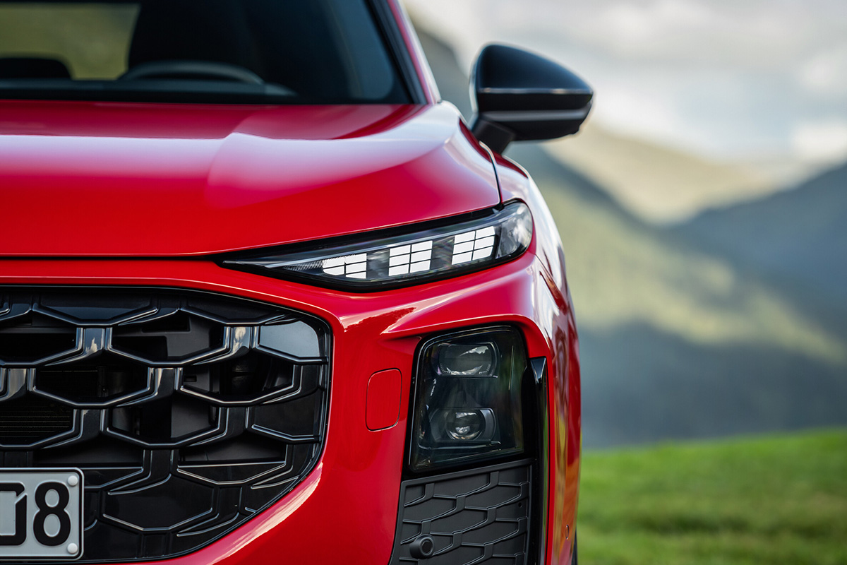 Rdeč Audi Q3 SUV, sprednji del z LED žarometi in značilno masko.