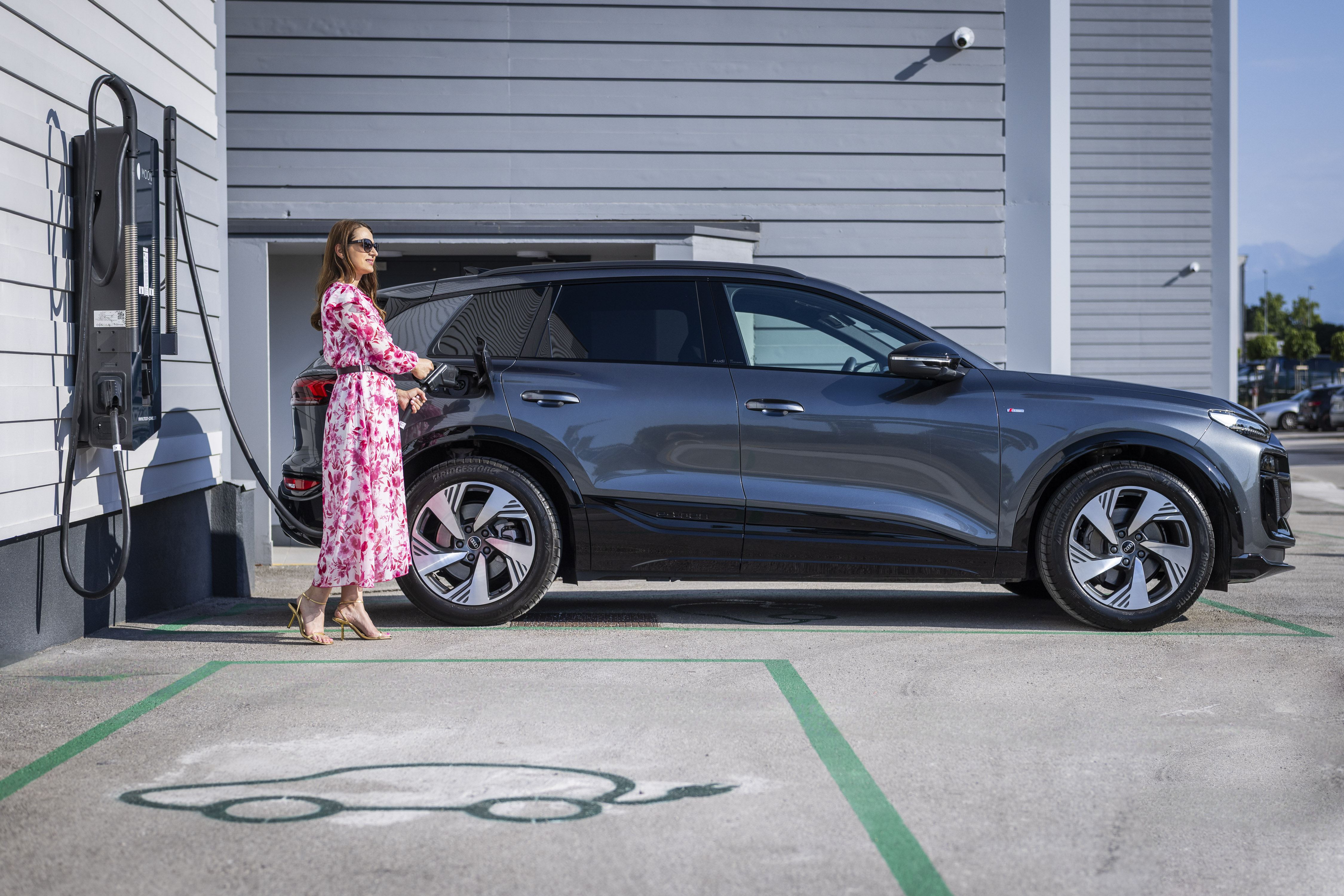Mirela Zupančič, vodja znamke MOON, polni Audi Q6 e-tron na službeni polnilni postaji.