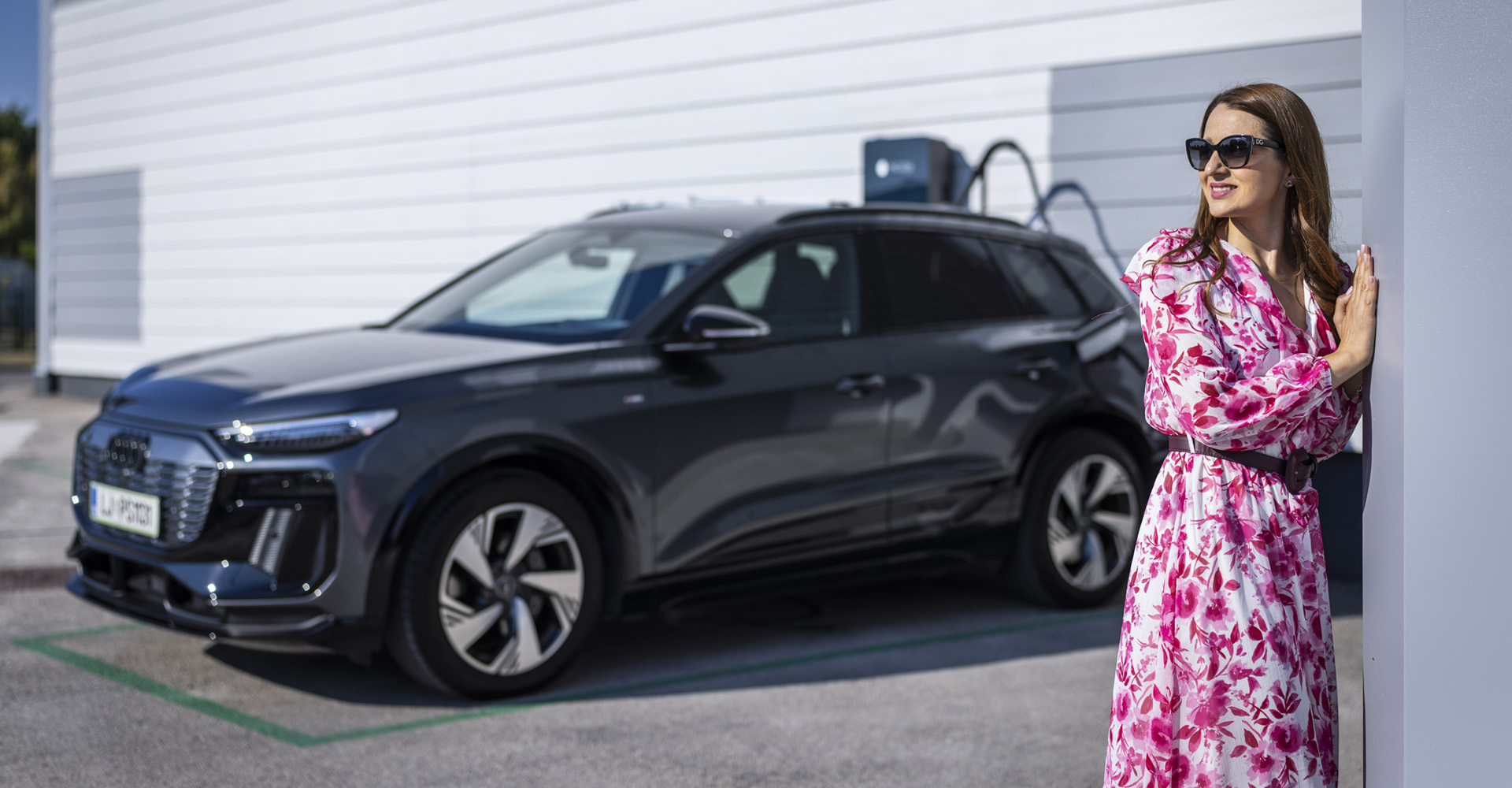 Mirela Zupančič stoji ob Audi Q6 e-tron na polnilnem mestu.