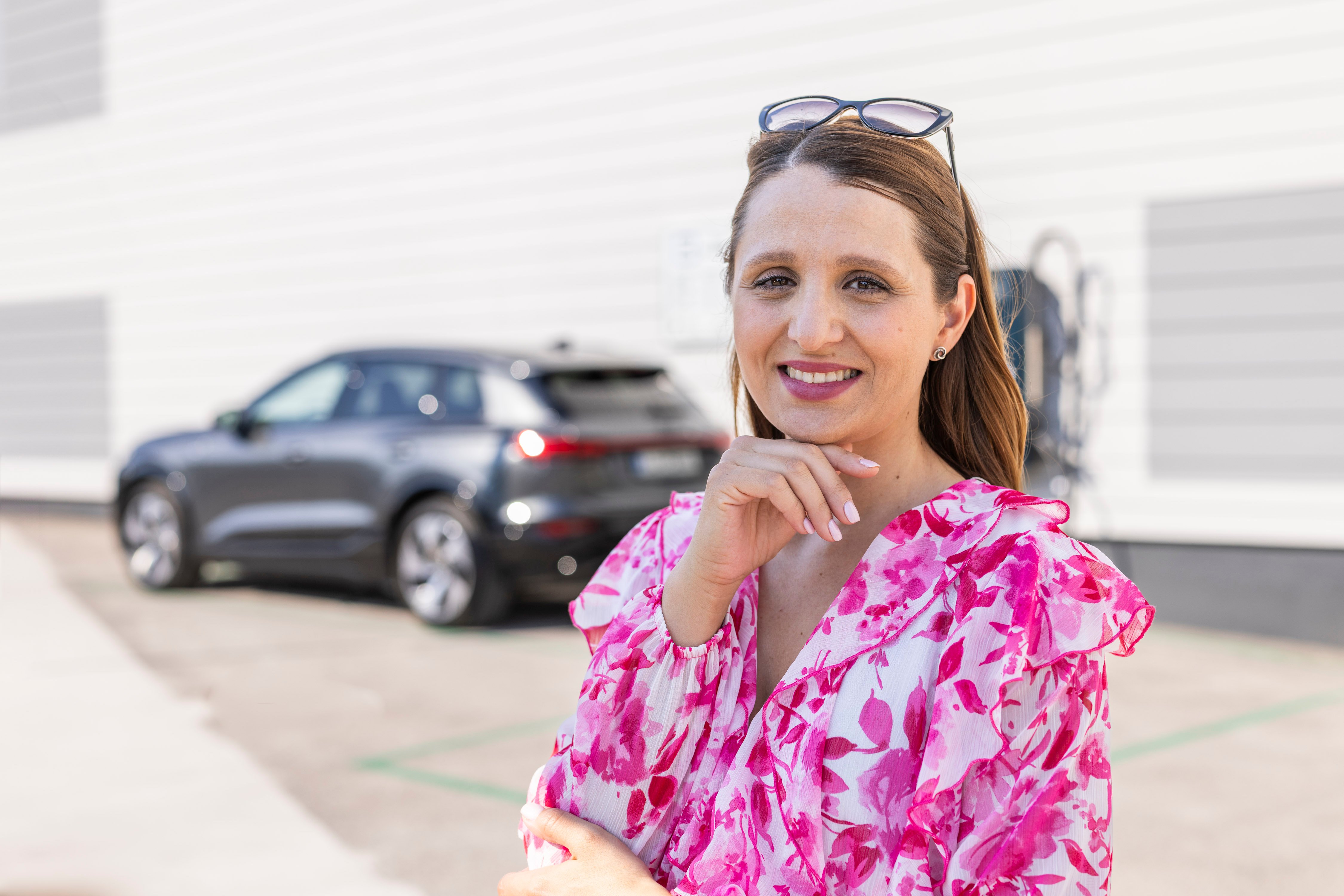 Mirela Župančič se nasmejano zadržuje pred parkiranim Audijem Q6 e-tron.