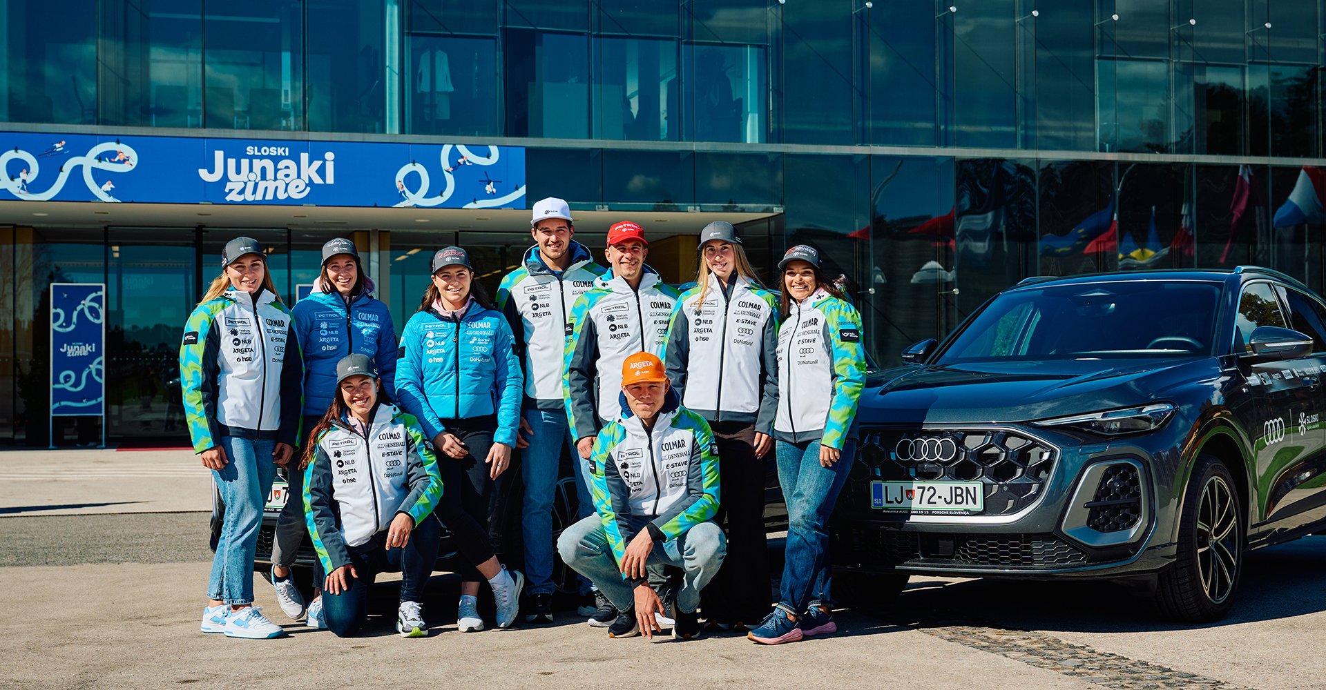 Slovenska smučarska ekipa stoji ob Audi Q5.