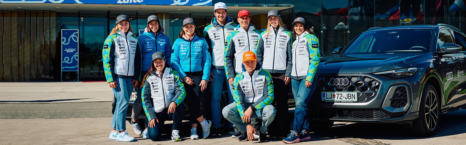 Slovenska smučarska ekipa stoji ob Audi Q5.